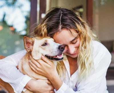 A woman in a white shirt hugging a dog.
