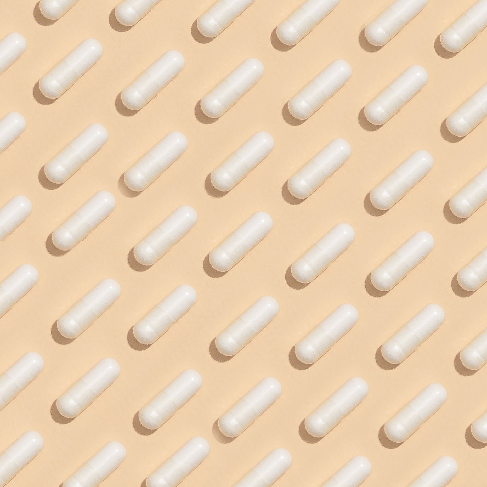 Pills laid out on a tan background in a checkerboard pattern.